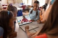 Diverse teacher and students looking at girl on laptop screen while studying online in classroom Royalty Free Stock Photo