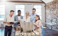 A diverse team of architects working on a building model together inside the office. A group of engineers planning a