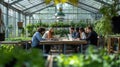 Diverse team collaborating on laptops in a modern greenhouse working on innovative projects Royalty Free Stock Photo