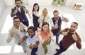 Diverse team of happy business people standing in office, looking up, smiling and giving thumbs up Royalty Free Stock Photo