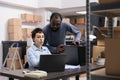 Diverse team talking about metallic box while checking transportation logistics for package delivery on laptop Royalty Free Stock Photo