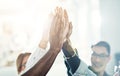 Diverse team of businesspeople high fiving together in an office