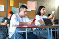 Diverse teenage high school students using phone in class to text message, use social media apps and take selfies. Royalty Free Stock Photo