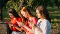 Diverse three girl friends using their phones outdoors. Group gen z young people using mobile smartphone sitting on Royalty Free Stock Photo