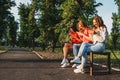 Diverse three girl friends using their phones outdoors. Group gen z young people using mobile smartphone sitting on Royalty Free Stock Photo