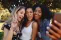 Portrait of a diverse happy smiling young beautiful women close friends having fun and taking selfie on mobile phone in Royalty Free Stock Photo