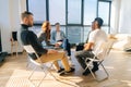 Diverse young colleagues sitting in circle have fun talking on business training with coach by window in light office Royalty Free Stock Photo