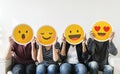 Diverse young people holding emoticon