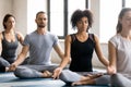 Diverse young people meditating, sitting in Lotus pose, practicing yoga