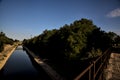 Diversionary channel with a railing and part of a road on a bridge in the countryside on a clear day at sunset