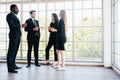 Diversity group of businesspeople strictly dressed in the suits standing meeting by office window. Royalty Free Stock Photo