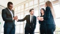 Diversity group of businesspeople strictly dressed in the suits standing meeting by office window. Royalty Free Stock Photo