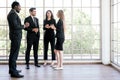 Diversity group of businesspeople strictly dressed in the suits standing meeting by office window. African and Caucasian. Royalty Free Stock Photo