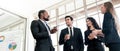 Diversity group of businesspeople strictly dressed in the suits standing meeting by office window. African and Caucasian. Royalty Free Stock Photo