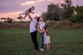 Diversity happy family plays in field at sunset. Young father lifting toddler high in the air Royalty Free Stock Photo