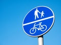 Divided path for cyclists and pedestrians blue road sign, object detail, closeup, isolated on blue sky background. Road signs