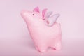 A divinely beautiful piggy angel with handmade wings stands on a white pink background close-up