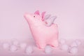 A divinely beautiful piggy angel with handmade wings stands on a white pink background with white soft balls in clouds