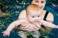 Diving baby in the paddling pool. Young mother, swimming instructor and happy little girl in pool. Learn infant child to Royalty Free Stock Photo