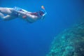 Diving girl underwater with coral reef. Snorkel in full face mask. Royalty Free Stock Photo