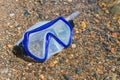Diving goggles lie on a river pebble, lost by someone