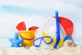 Diving mask with beach ball and toys in sand on blue Royalty Free Stock Photo