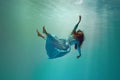 Diving into unknown. Surreal underwater scene featuring elegant young woman levitating gracefully underwater.