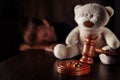 Divorce concept. Wooden gavel, rings and frustrated boy with teddy bear. Family divorce effect on children