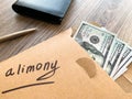 Divorce and separation concept. Alimony written on an envelope with dollars.