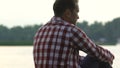 Divorced man sitting on river bank thinking about life injustice, midlife crisis