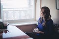 Diwa angel mystic lady woman wearing casual blue dress lonely sitting in restaurant caffe with coffe cup awaiting her boyfreind hu Royalty Free Stock Photo