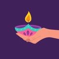 Diwali diya lamp. Female hand holding burning candle. Indian festival of lights icon. Colorful deepavali sign on purple Royalty Free Stock Photo