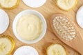 Diy banana mask face cream in the small white bowl, wooden hair brush, cotton pads and banana slices.