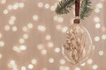 Diy baubles filled dried florals, grass, toy hanging on green fir. Glass Christmas ornaments on bokeh texture background