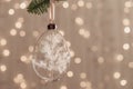 Diy baubles filled dried florals, grass, toy hanging on green fir. Glass Christmas ornaments on bokeh texture background
