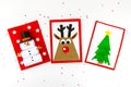 DIY Christmas cards kids. Three cards with a Christmas tree, a deer, a snowman from colored paper