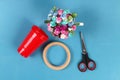 Diy Easter egg basket made of red plastic cup decorated with artificial flowers on blue background Royalty Free Stock Photo