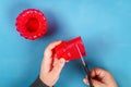 Diy Easter egg basket made of red plastic cup decorated with artificial flowers on blue background Royalty Free Stock Photo