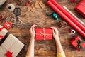 DIY Gift Wrapping. Woman wrapping beautiful red christmas gifts on rustic wooden table. Overhead point of view.