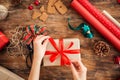 DIY Gift Wrapping. Woman wrapping beautiful red christmas gifts on rustic wooden table. Overhead point of view.