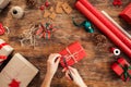 DIY Gift Wrapping. Woman wrapping beautiful red christmas gifts on rustic wooden table. Point of view of christmas wrapping.