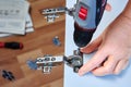 DIY installation adjustable door hinges on cabinet of flat pack, using power screwdriver.