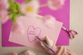 DIY mom card. Mothers Day.Child draws a heart on a pink piece of paper and writes mom I love you. daughter makes a card Royalty Free Stock Photo