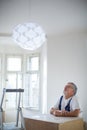 Senior landlord hanging a new light in a rental appartement Royalty Free Stock Photo