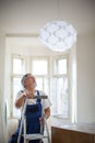 Senior landlord hanging a new light in a rental appartement Royalty Free Stock Photo