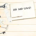 Diy and save! against tools and notepad on wooden background