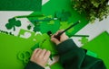 DIY St.Patricks Day decor. A boy draws with a pencil craft card from shamrocks of green paper. Selective focus
