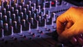 Hand Settings Volume Level Controls on Mixing Console Faders Neon Light Close-Up