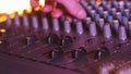 Hand settings volume level controls on mixing console faders neon light close-up