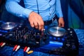 DJ hand controls volume and mix music in professional mixer in nightclub at party